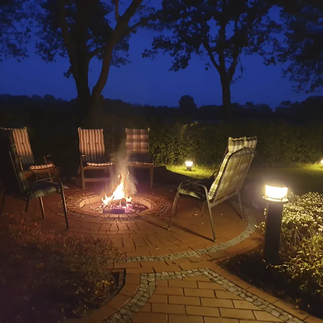 Brennendes Lagerfeuer zwischen Gartenstühlen in der Abenddämmerung